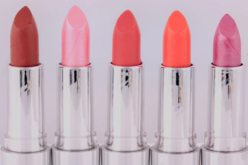 Seven similar lipsticks beside one different shade and an open make-up pouch.