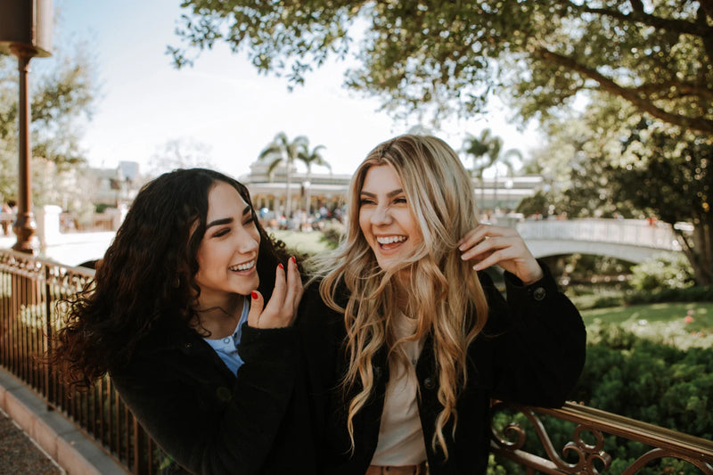 Friends laughing together safely on a pavement near a crossing.